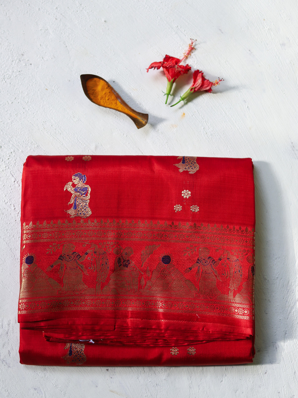 Traditional Handwoven Swarnachari Mulberry silk wedding saree for bengali bride in Red saree with gold patterns on a light gray background