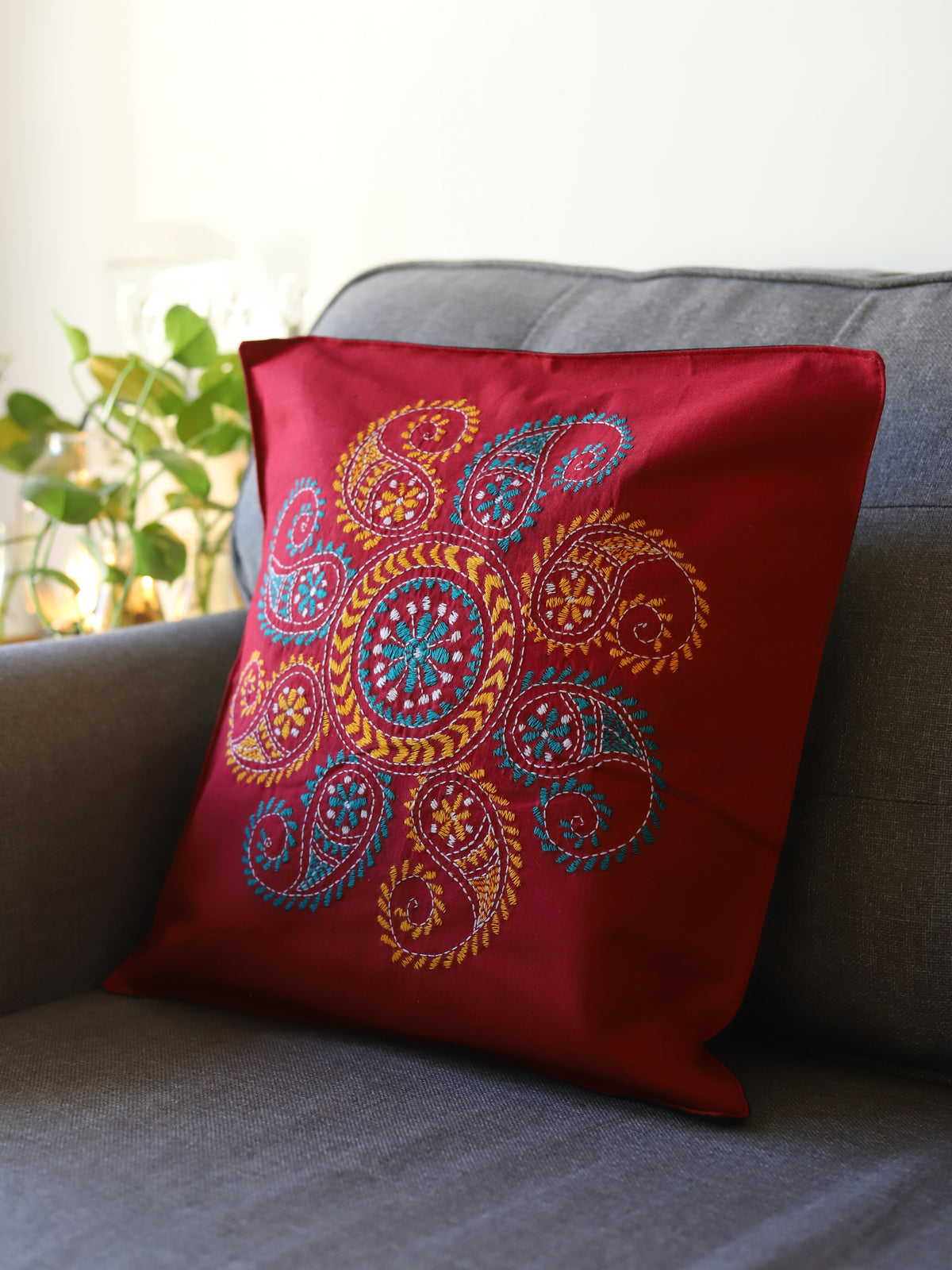 Red pillow with colorful paisley pattern on a gray couch