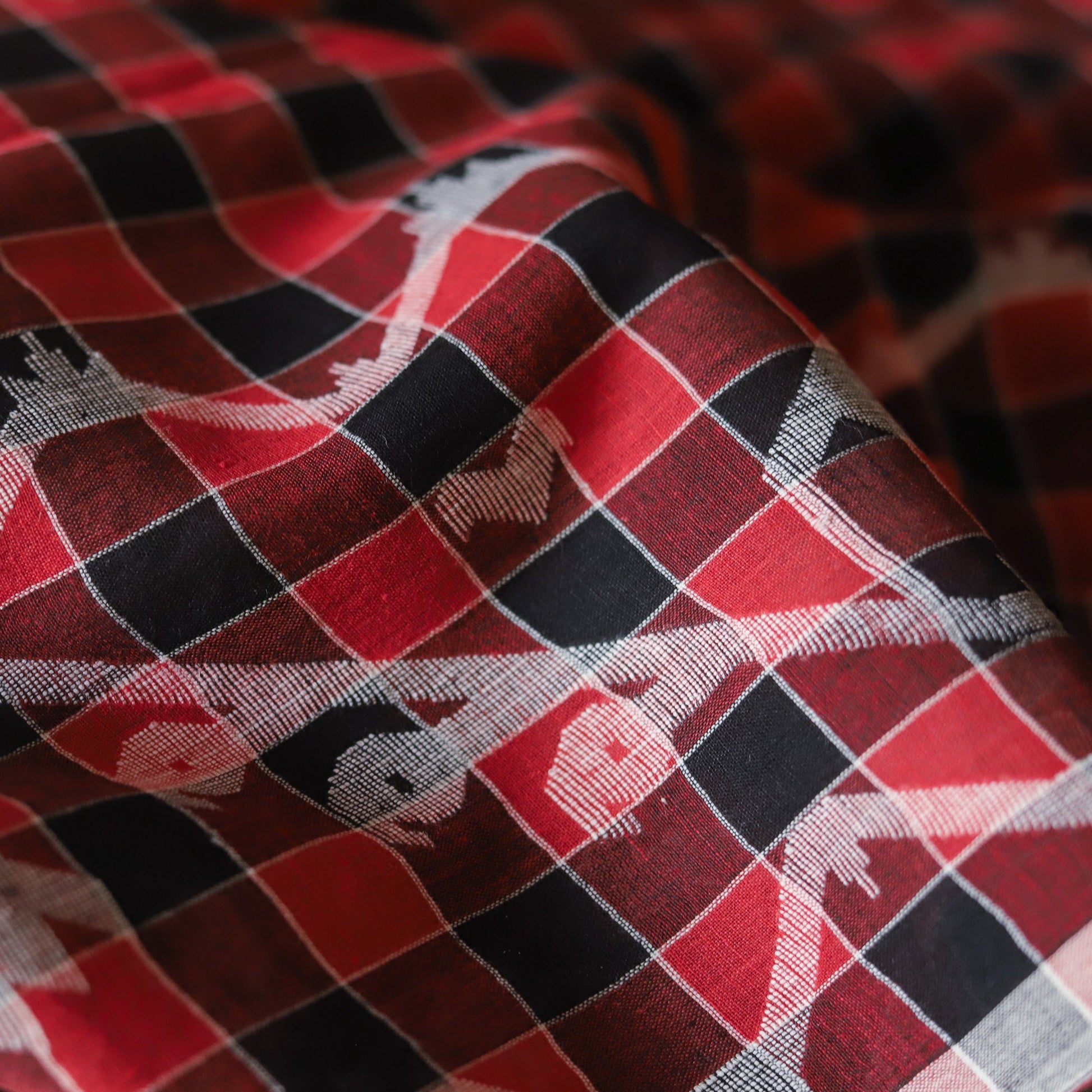 Close-up of red, black, and gray checkered fabric with small animal prints.