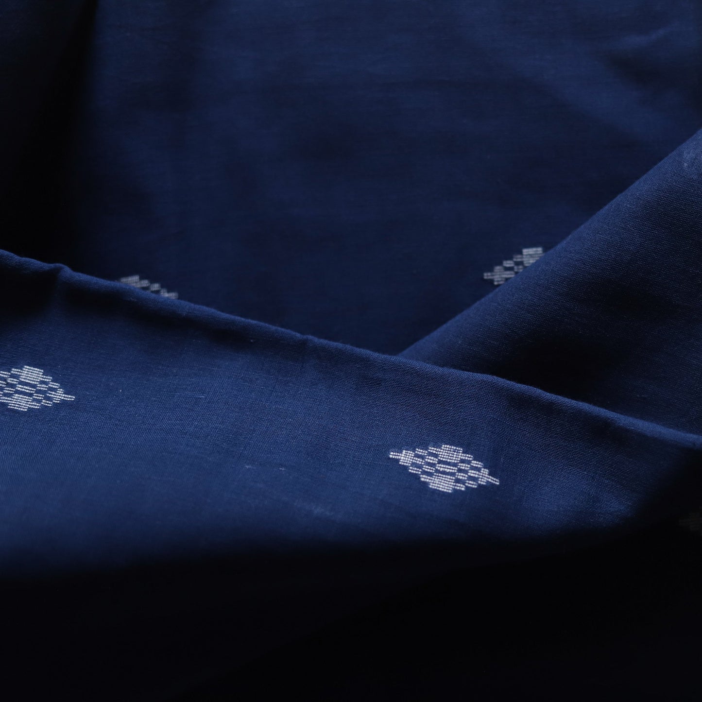 Close-up of dark blue fabric with subtle white floral patterns