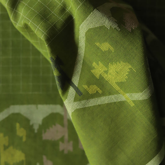 Close-up of a green handwoven Bengal Jamdani cotton fabric with patterns on a dark background