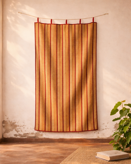 Striped curtain hanging on a rod against a textured wall with a plant and book on a rug.