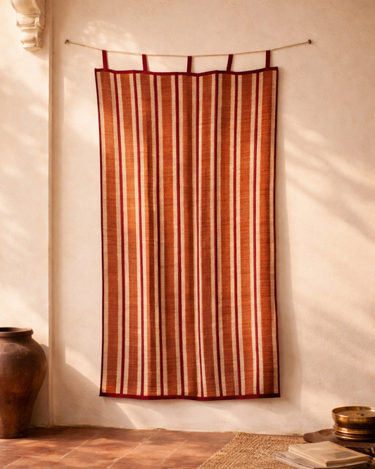 Striped fabric hanging on a rod against a white wall with a wooden floor.
