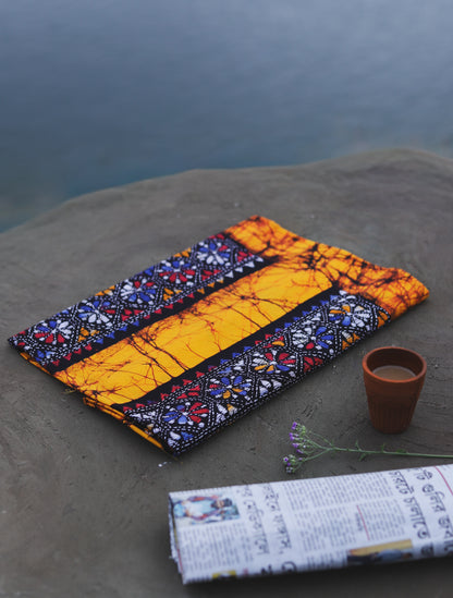 Decorative Batik Kantha Cotton Kurta Fabric with geometric pattern on a stone surface next to a cup of coffee and rolled-up newspaper.