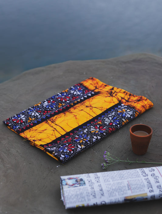 Decorative Batik Kantha Cotton Kurta Fabric with geometric pattern on a stone surface next to a cup of coffee and rolled-up newspaper.
