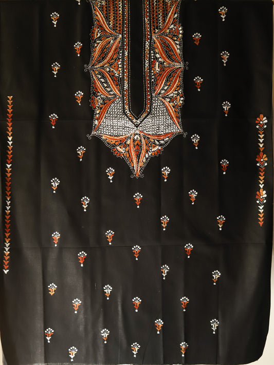 Black fabric with intricate orange and white embroidery on a dark background