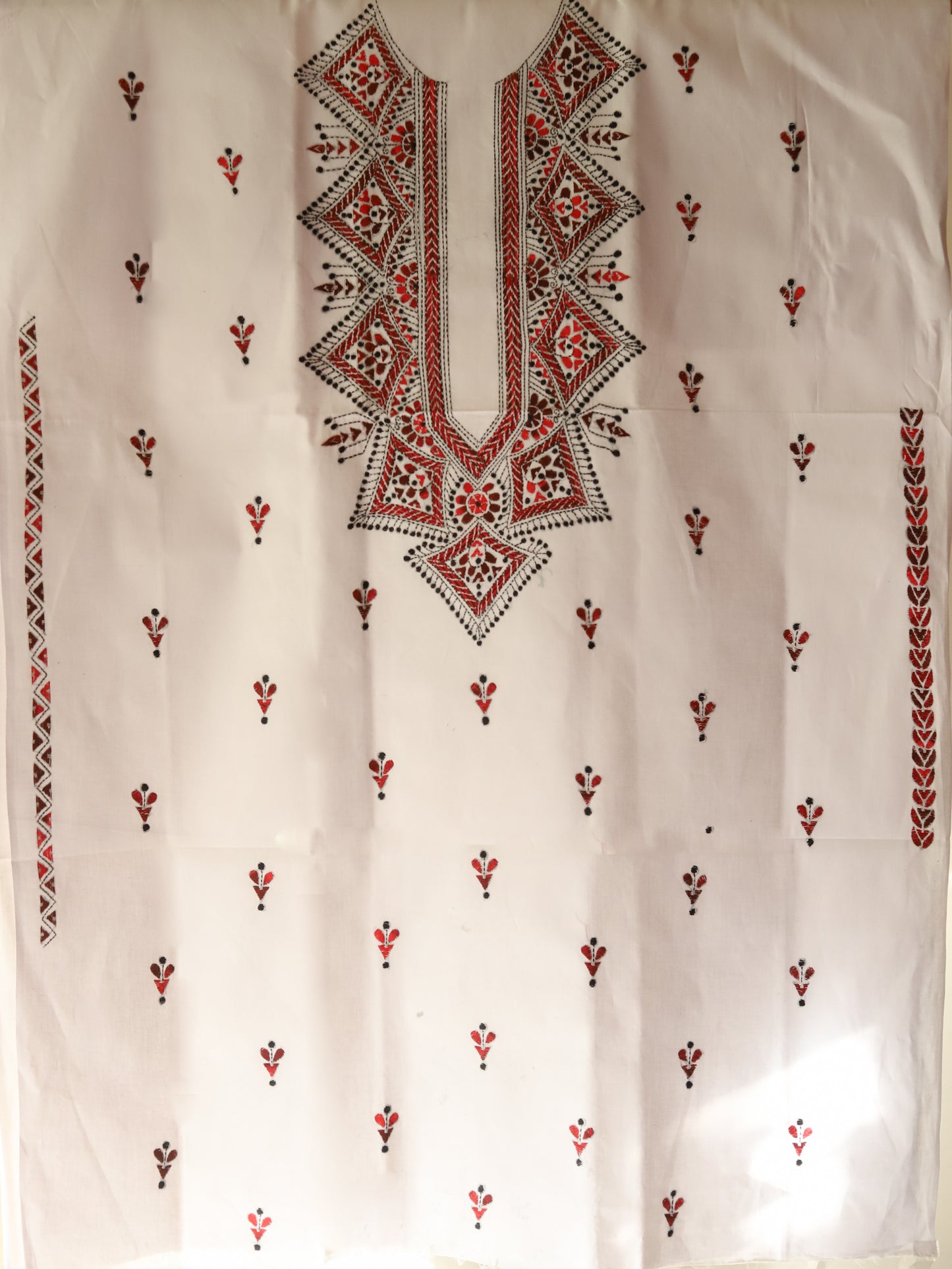 White fabric with intricate multicolored embroidery on a plain background