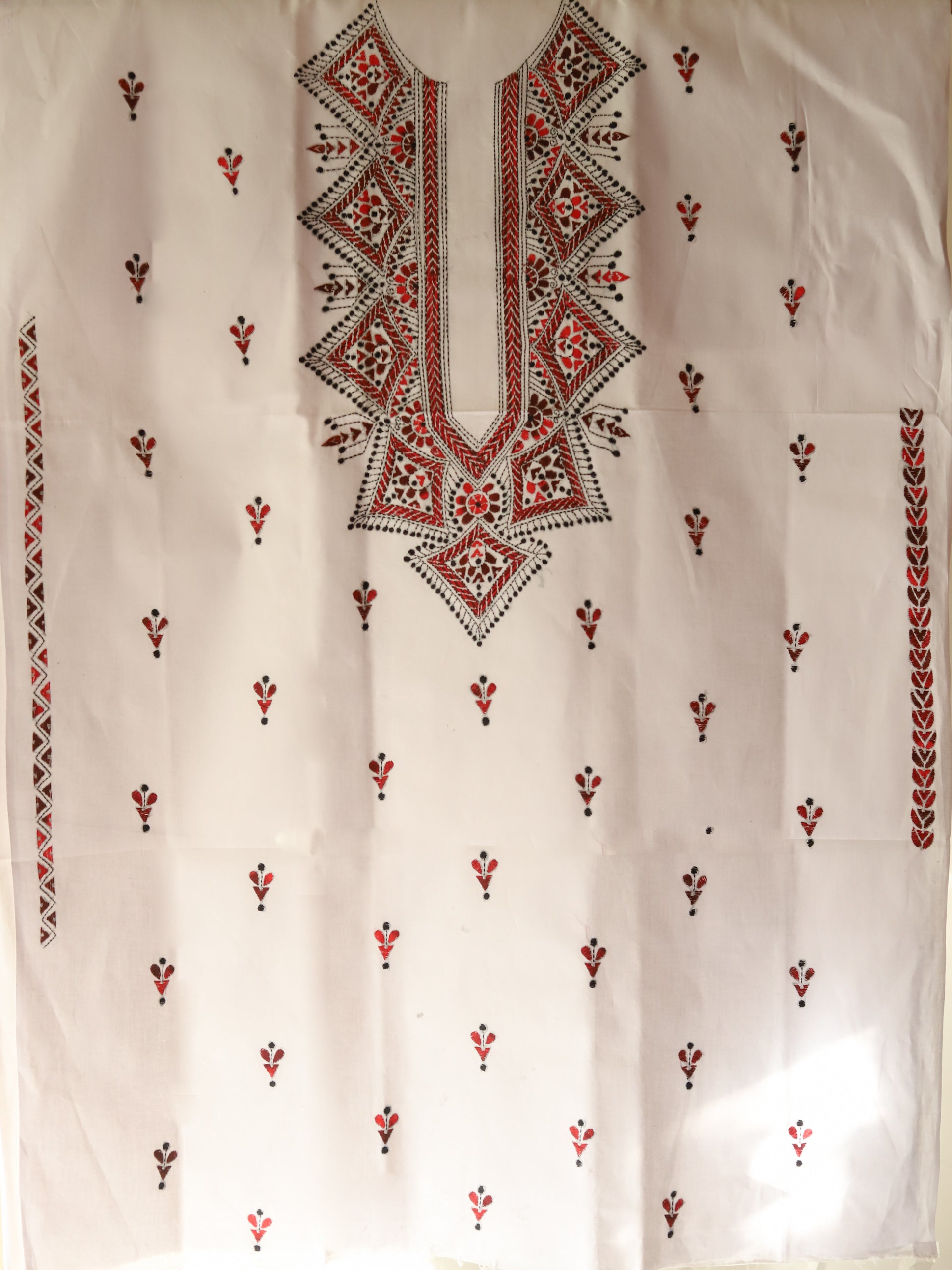 White fabric with intricate multicolored embroidery on a plain background