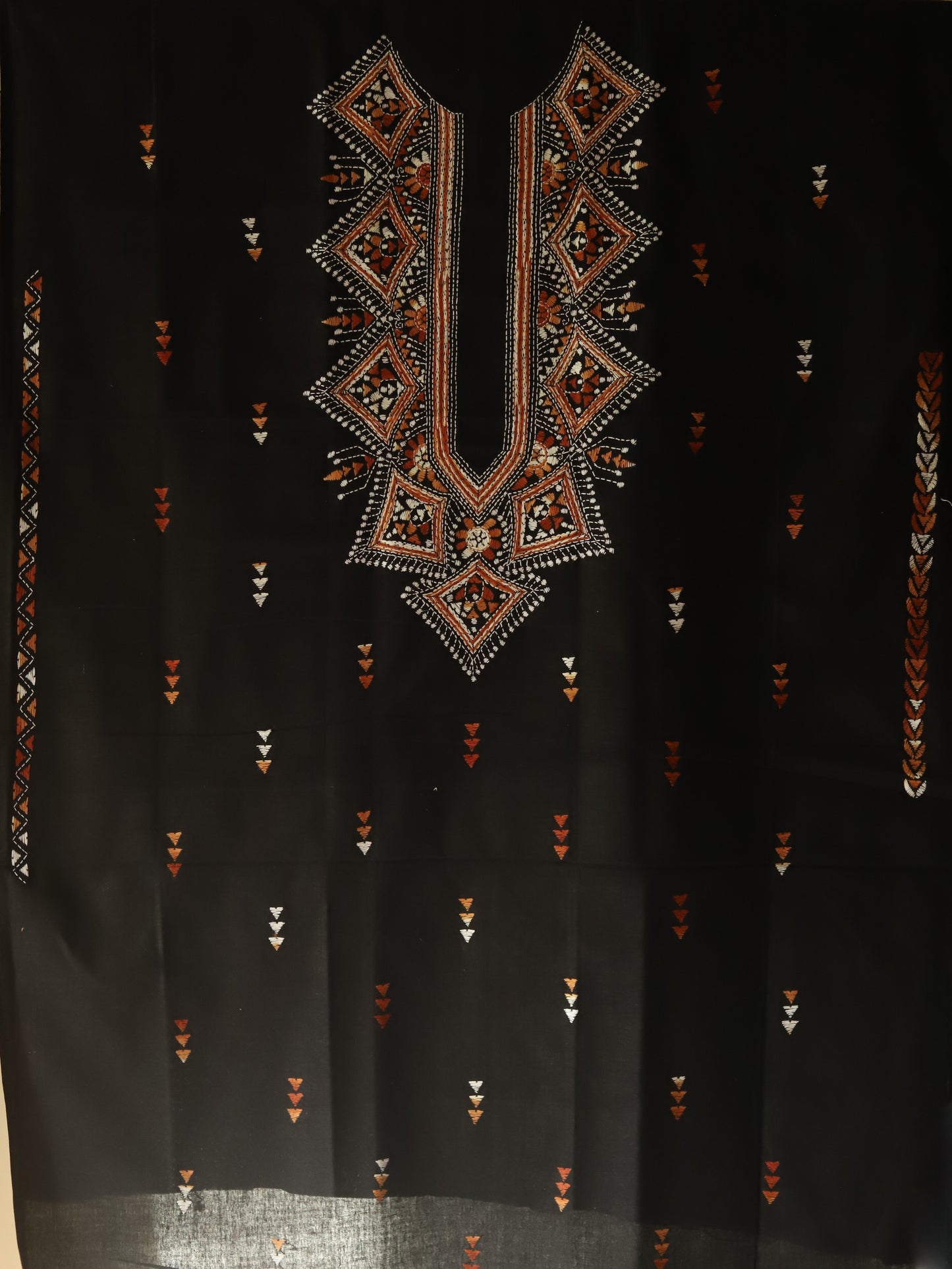 Black fabric with intricate geometric embroidery in brown and gold