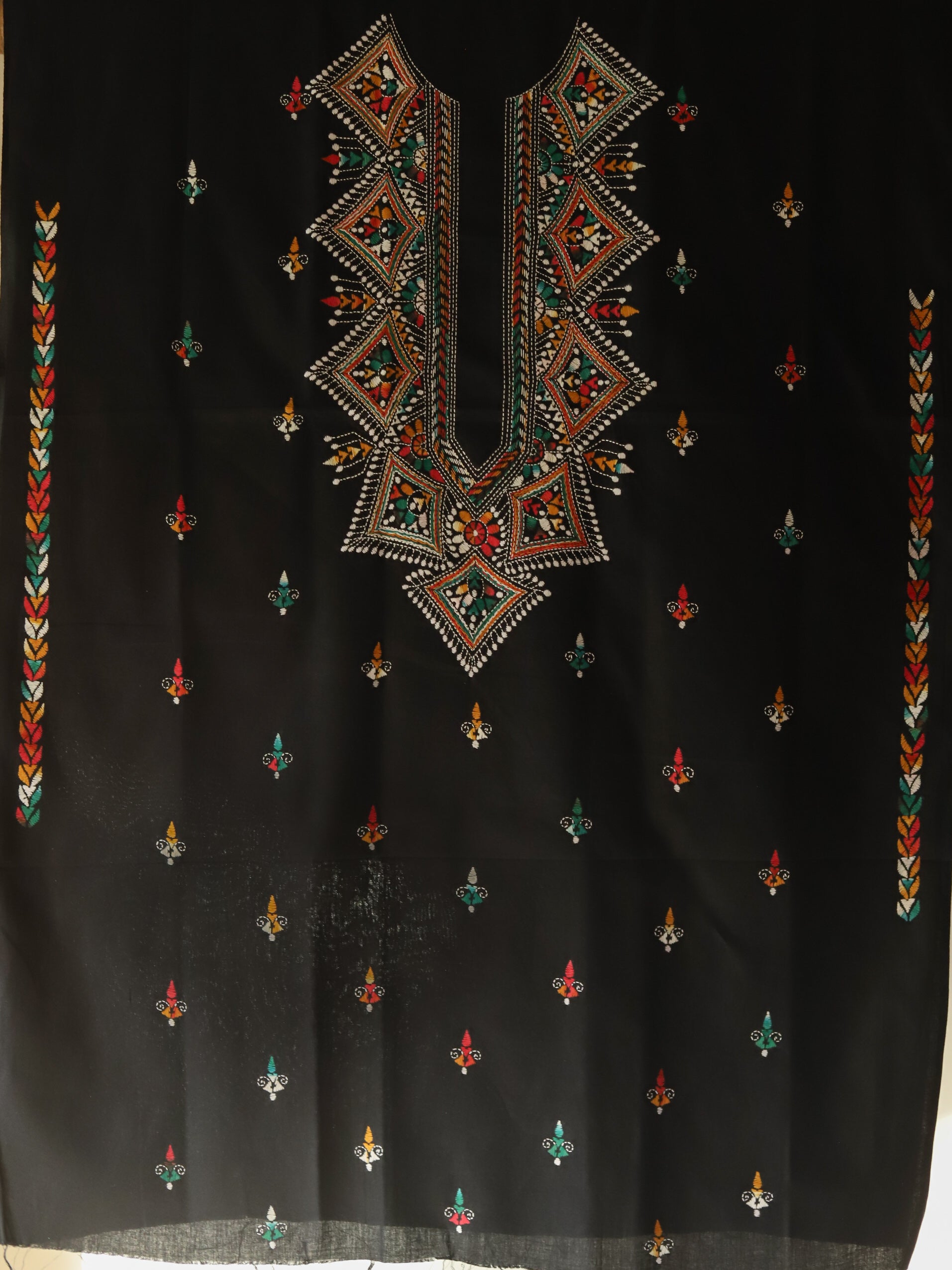 Black fabric with intricate multicolored embroidery on a plain background