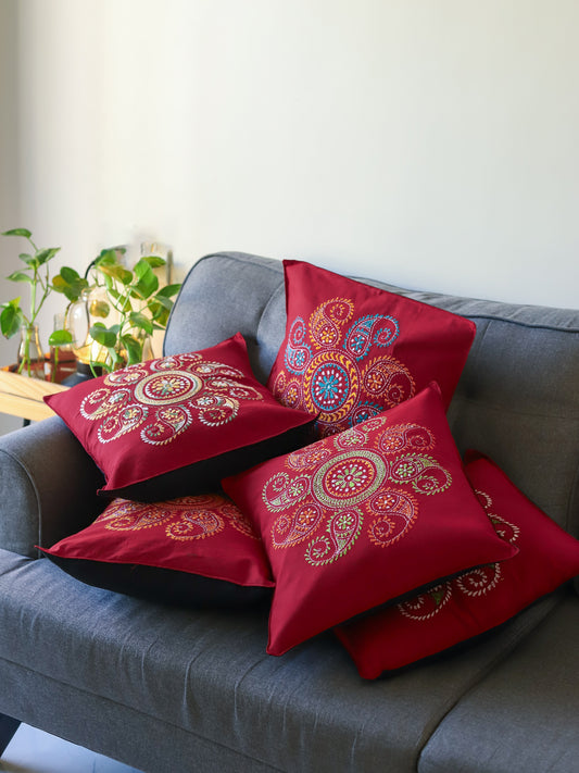 Bengal red patterned hand embroidery kantha cushions on a grey sofa with a neutral background next to green plants
