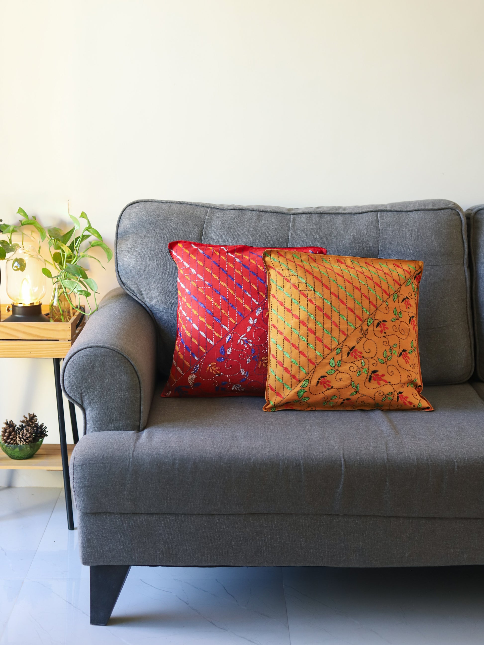 Gray sofa with colorful hand emberoidered Bengal kantha pillows in a room setting