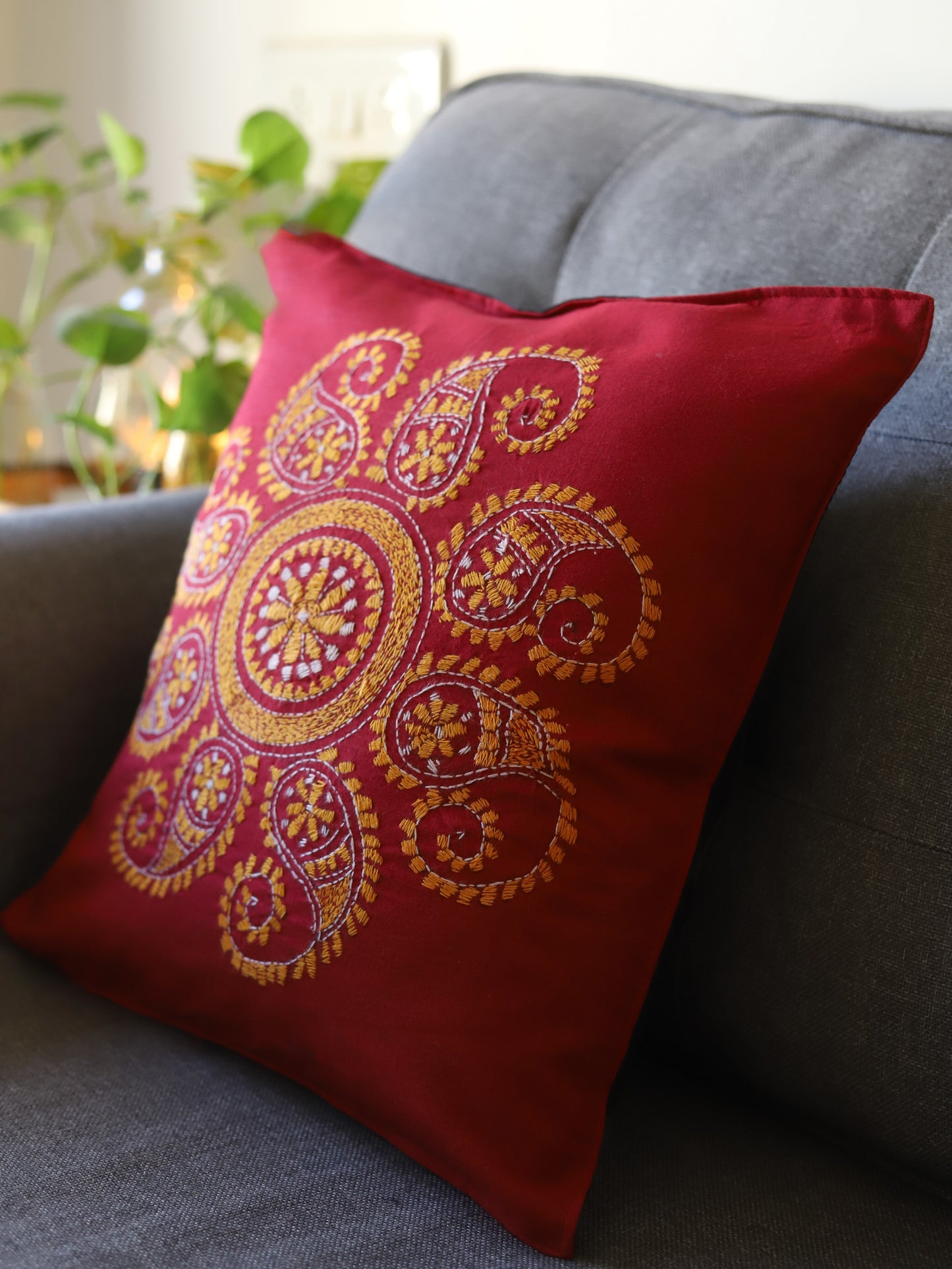Red pillow with gold embroidery on a gray couch