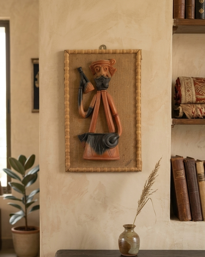 Decorative wall piece of a man with a weapon on a textured wall with books and a plant.