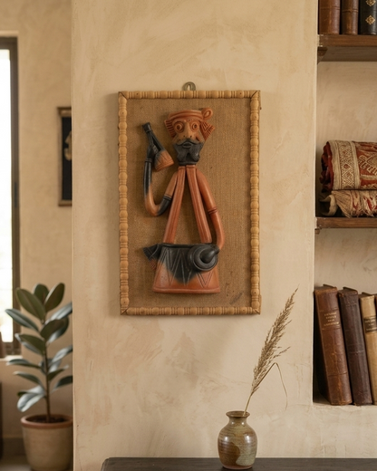 Decorative wall piece of a man with a weapon on a textured wall with books and a plant.