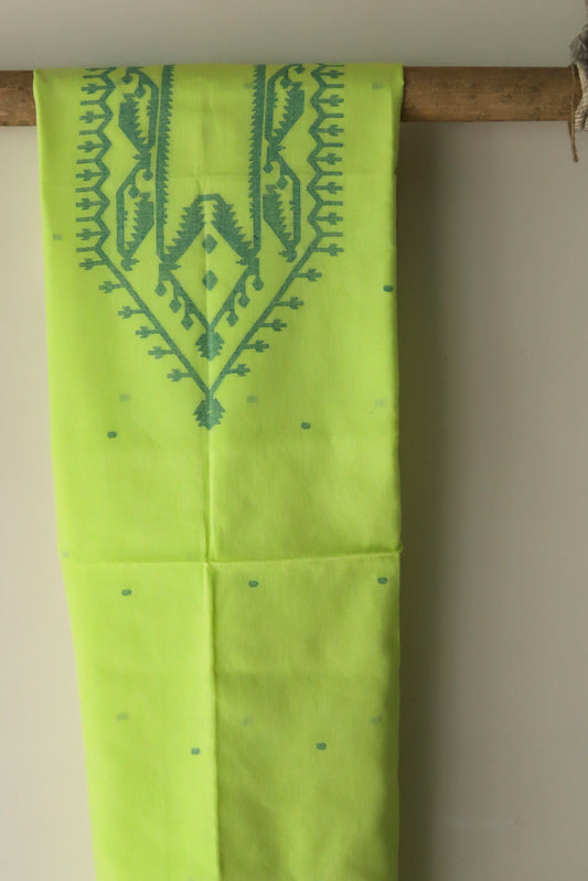 Green fabric with intricate patterns hanging on a wooden rod against a beige wall.