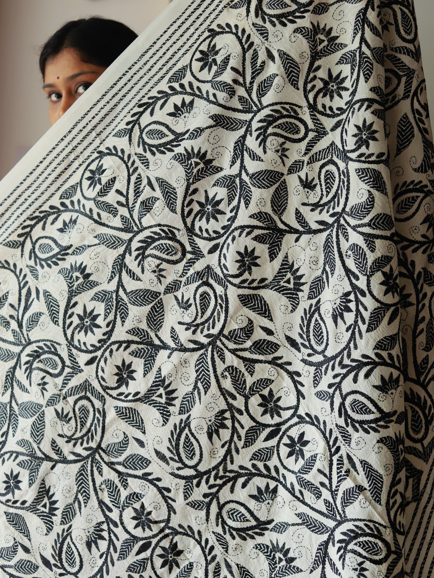 Person holding a large piece of fabric called dupatta with black floral pattern on white background