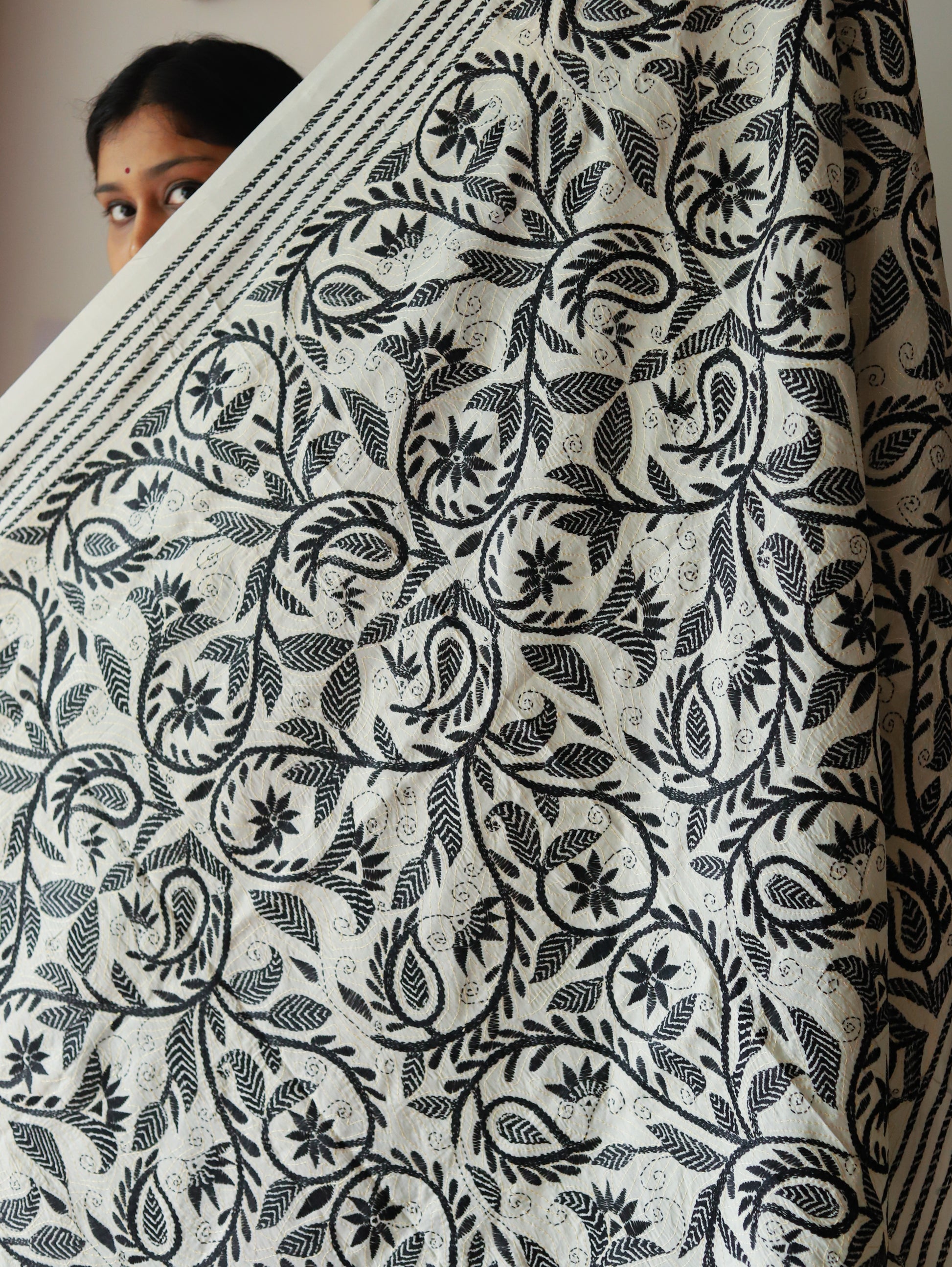 Person holding a large piece of fabric called dupatta with black floral pattern on white background