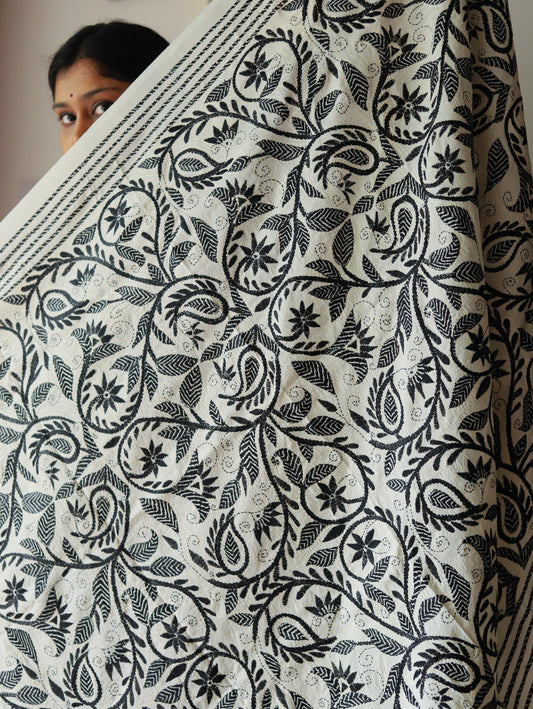 Person holding a large piece of fabric called dupatta with black floral pattern on white background