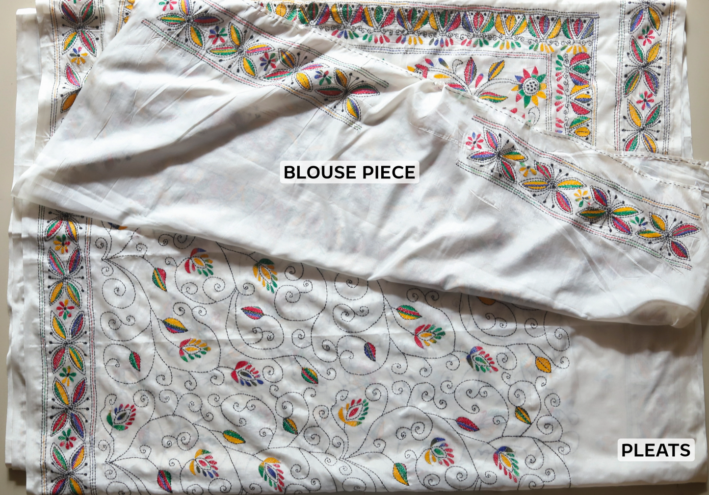 White blouse piece with colorful floral patterns on a plain background